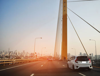 Vehicles on road against sky in city