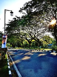 Street by trees against sky in city