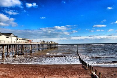 Pier on sea against cloudy sky