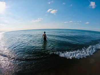 Rear view of man standing in sea against sky