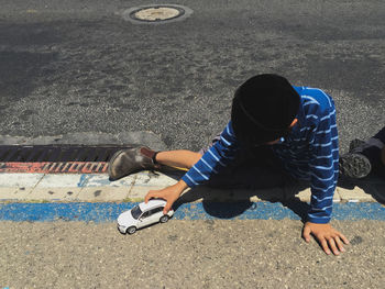 High angle view of boy playing with toy car on footpath