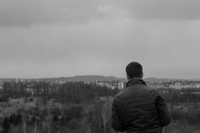 Rear view of man standing on landscape against sky