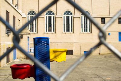 Basketball hoop against building seen through chainlink fence