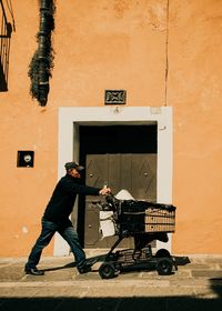 Man with umbrella standing against wall