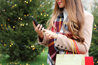 Midsection of woman holding mobile phone outdoors