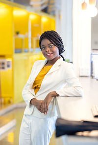 Portrait black woman in modern office in coworking background, afro woman in yellow sweater