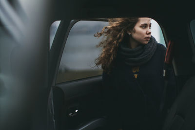 Beautiful woman wearing scarf standing at car door