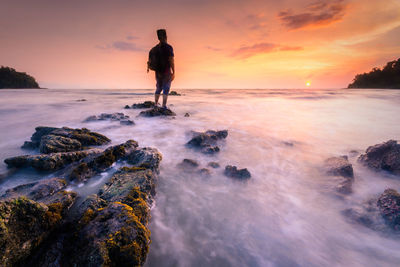 Man looking at sea against sky during sunset