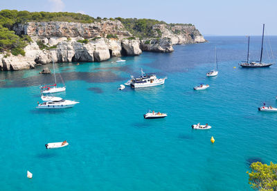 Boats sailing in sea against clear blue sky