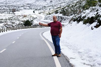 Portrait of man gesturing while standing on road during winter