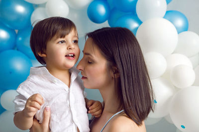 Mom and son on their birthday having fun at home with balloons and number two