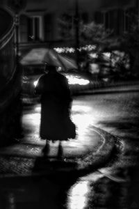 Rear view of people walking on street at night