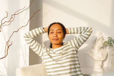 Smiling african-american female looking at window. natural light from sunset. enjoying moment