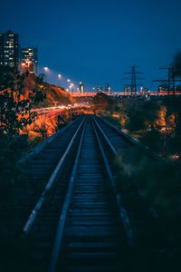Empty railroad tracks in city at night