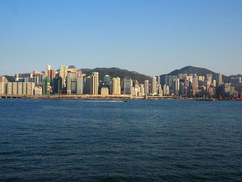 Sea by city against clear sky