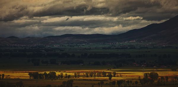 Scenic view of landscape against storm clouds