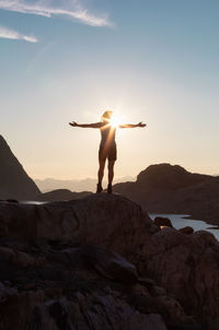 Man standing on rock against sky during sunset