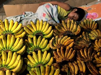 High angle view of boy sleeping by bananas on table