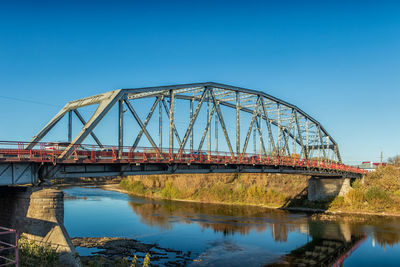 Bridge over river against clear blue sky