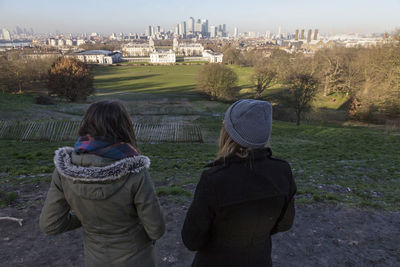 Rear view of female friends standing on field