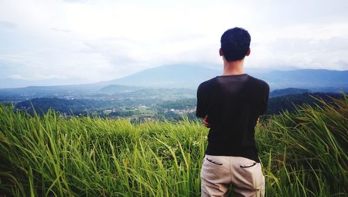 Rear view of man standing on field against sky