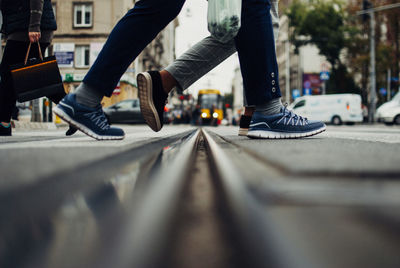 Low section of people walking on street in city