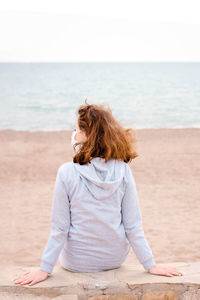 Rear view of woman sitting on beach