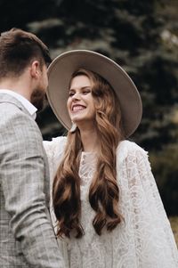 Smiling bride looking at groom against trees