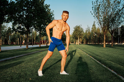 Full length of shirtless man exercising on field