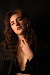 Portrait of young woman against black background