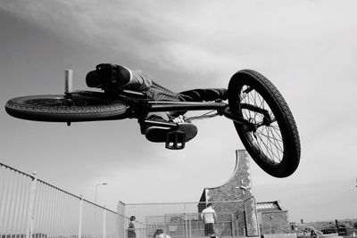 Low angle view of man performing stunt on bicycle against sky