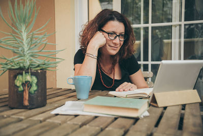 Young woman sitting on table at home