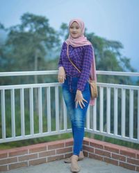 Portrait of smiling woman standing on footbridge