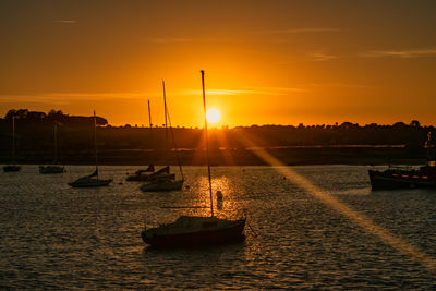 Boats at harbor against sky during sunset