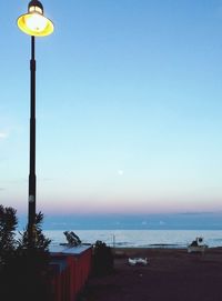 Street light by sea against clear sky