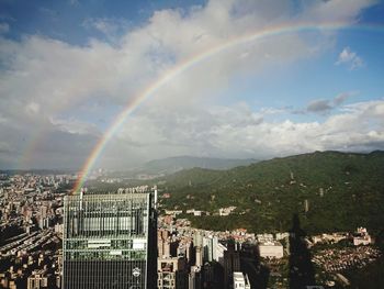 Rainbow over buildings in city against sky