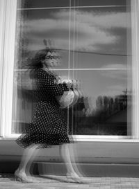 Rear view of woman looking through window