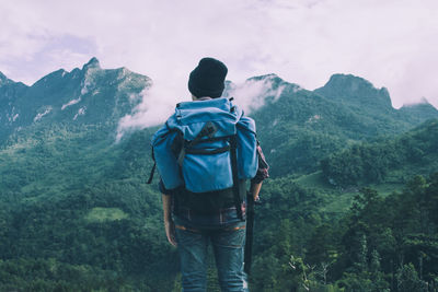 Rear view of man standing on mountain against sky