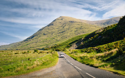  landscape scenery  white car driving on  scenic road trough nature at delphi, county mayo, ireland