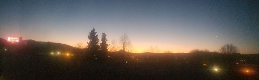 Silhouette trees on field against clear sky during sunset