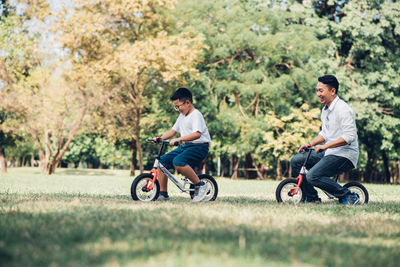 Boy riding bicycle with father on grass