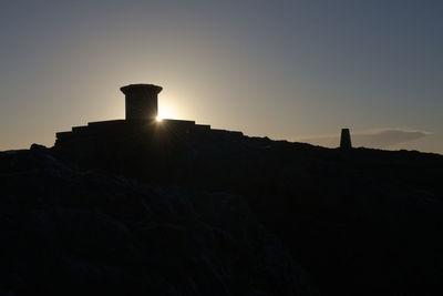 Silhouette rock formations against sky during sunset