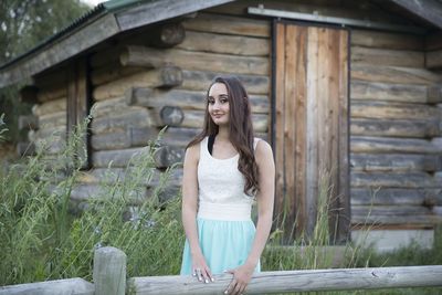 Portrait of young woman standing against wall