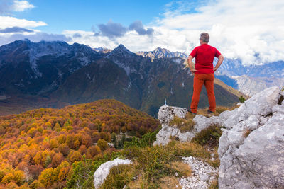 Rear view of man with hands on hip looking at landscape during autumn