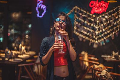 Midsection of woman drinking glass at night