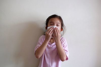 Portrait of a girl standing against wall