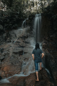 A man standing in front of a waterfall travel image