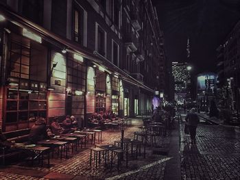 Illuminated road against buildings at night