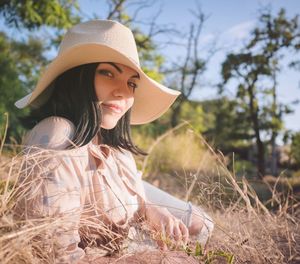 Portrait of beautiful woman wearing hat lying on field