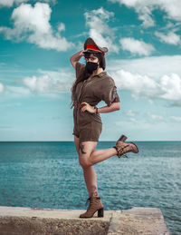 Woman standing by sea against sky